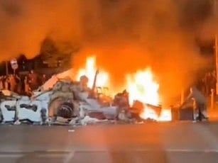 X : A police car was flipped on its side and a bus was set on fire alight after unrest broke out.

